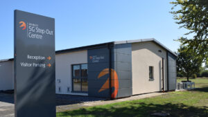 Building with "Westcott 5G Step-Out Centre" signage, gray exterior, and grassy surroundings under a clear sky.