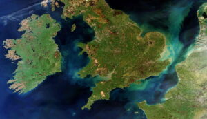 Satellite view of Great Britain and Ireland surrounded by blue and green waters on a clear day.