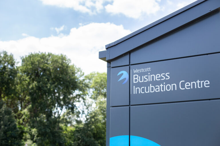 Sign for Westcott Business Incubation Centre with trees and cloudy sky in the background.