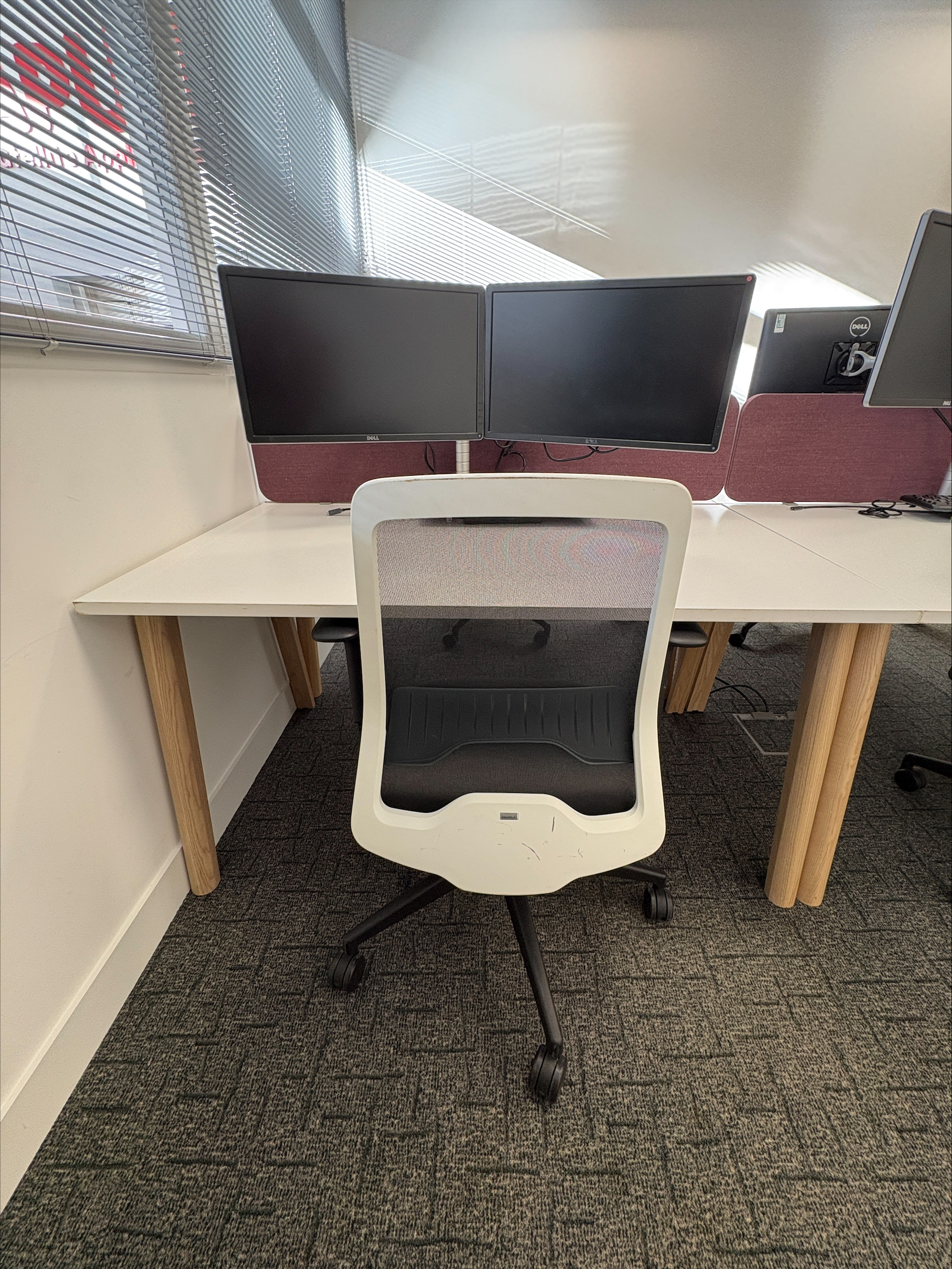 Office chair facing a desk with two computer monitors and a keyboard in a modern workspace.