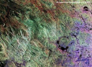 Satellite view of a colorful, textured landscape with green, brown, and purple hues, © Copernicus Sentinel data (2019)/ESA.