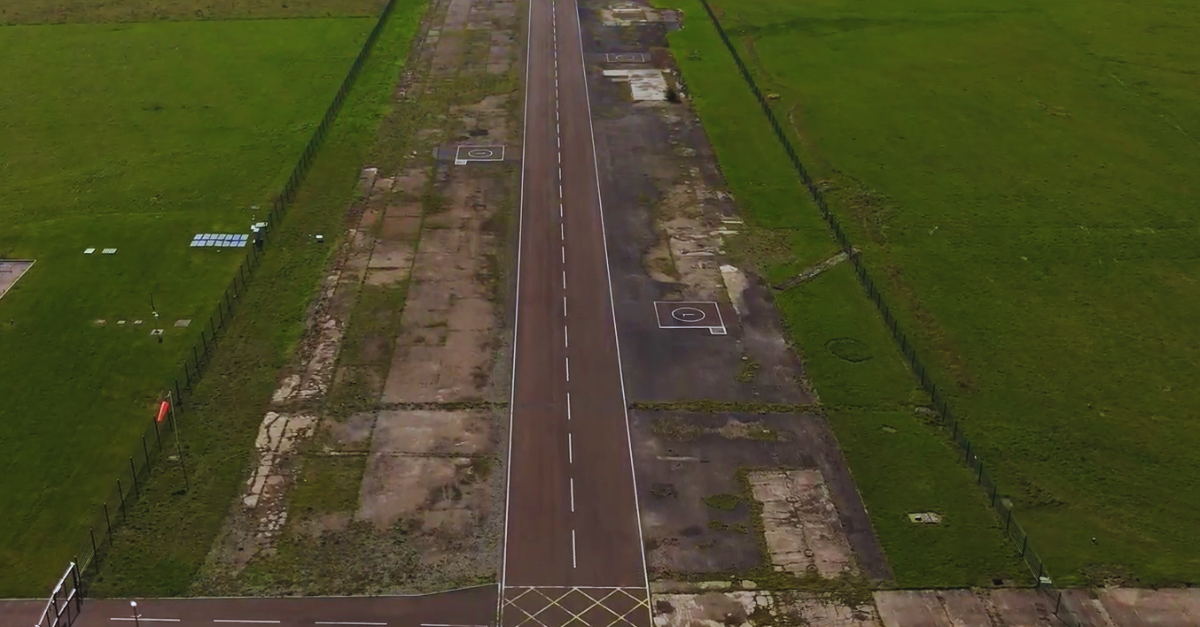 Aerial view of an old, worn runway surrounded by green grass fields.