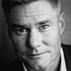 Black and white close-up of a man with short hair and a serious expression.