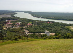 View from a hill of a river winding through lush green landscape, with buildings scattered in the scenery.