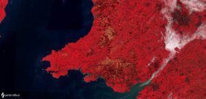 Infrared satellite image of Wales with red hues indicating vegetation and blue-green areas representing water.