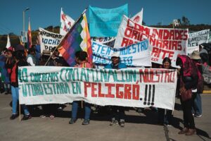 Protesters holding colorful banners and flags with messages against pollution at a rally.
