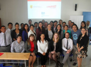 Group of people posing indoors in front of a projected presentation slide.