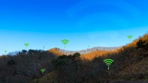 A hilly landscape with Wi-Fi symbols hovering over it under a clear blue sky.