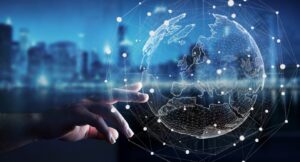 A hand reaches towards a digital, networked representation of Earth against a blurred cityscape background.