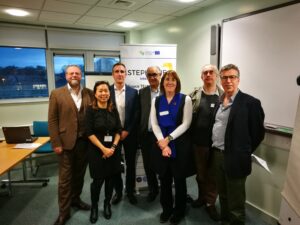 Seven people standing together in an office setting, smiling at the camera.