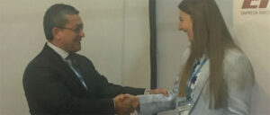 Two people in business attire shaking hands and smiling at an event or meeting.