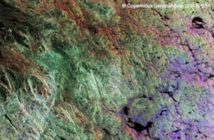 Aerial view of colorful geological patterns with green, purple, and brown hues. Copernicus Sentinel data, ESA 2019.