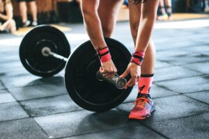 Person adjusting weights on a barbell in a gym, wearing pink socks and shoes, on a rubber gym floor.