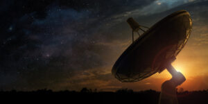 Silhouette of a satellite dish against a starry sky and sunset.