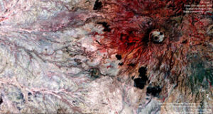 Satellite image of a volcanic landscape with red hues indicating lava flows and varied terrain textures.