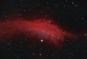 Red nebula resembling ocean waves against a starry black sky.