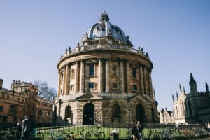 The Radcliffe Camera in Oxford, UK on a sunny day, with people and bicycles in the foreground.