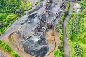 Aerial view of a quarry with machinery, surrounded by lush greenery and a winding road.