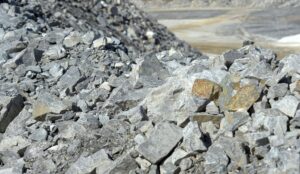 A pile of gray rocks and stones in a quarry setting under bright daylight.