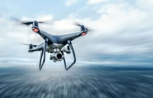 A drone with a camera flying over a blurred, fast-moving landscape under a cloudy sky.