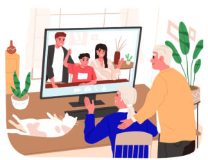 Elderly couple video calls family on a computer; a cat sleeps on the desk nearby.