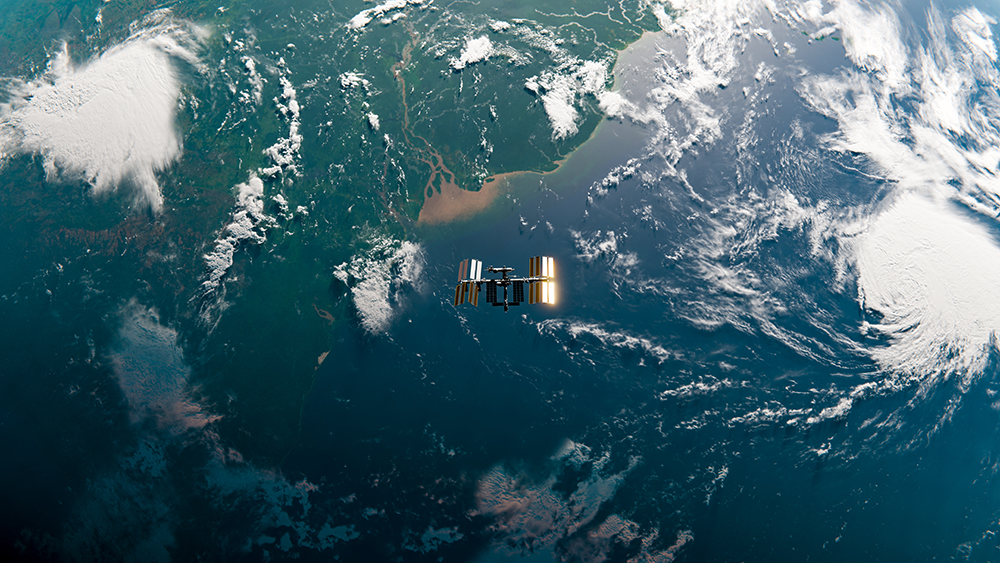 Satellite orbiting above Earth, with visible land, clouds, and water from a space view.