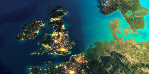 Satellite view of the UK and parts of Europe at night with illuminated cities and a bright blue sea.