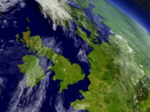 Satellite view of the British Isles and part of Europe, with green land, blue seas, and scattered clouds.