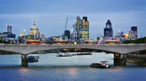London skyline with illuminated cityscape, St. Paul's Cathedral, The Gherkin, and a bridge over the Thames at dusk.