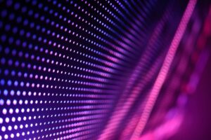 Abstract pattern of pink and purple dots creating a wave-like effect on a dark background.