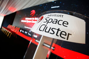 Stage setup for "Westcott Space Cluster" event with chairs and a large screen displaying space-themed graphics.