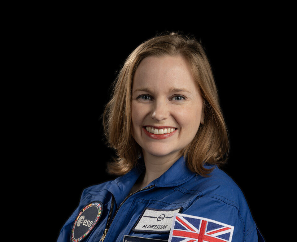 Astronaut Meganne Christian wearing a blue ESA flight suit with a British flag patch.