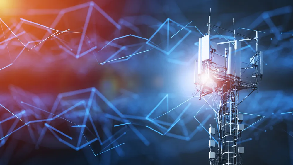 Cell tower with antennas against a digital network background and glowing blue and orange lights.