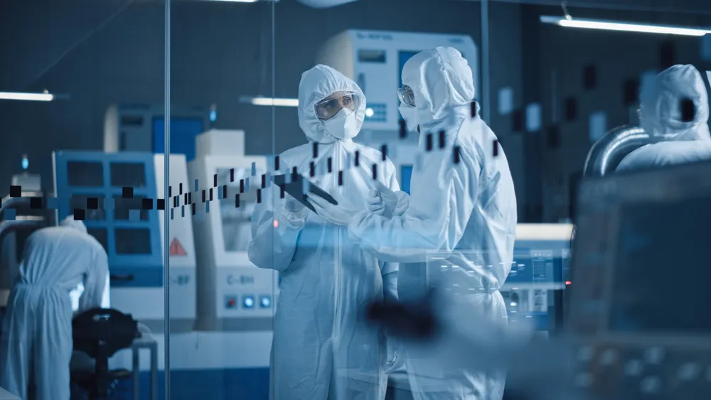 Scientists in full protective suits working and discussing data in a high-tech laboratory cleanroom.