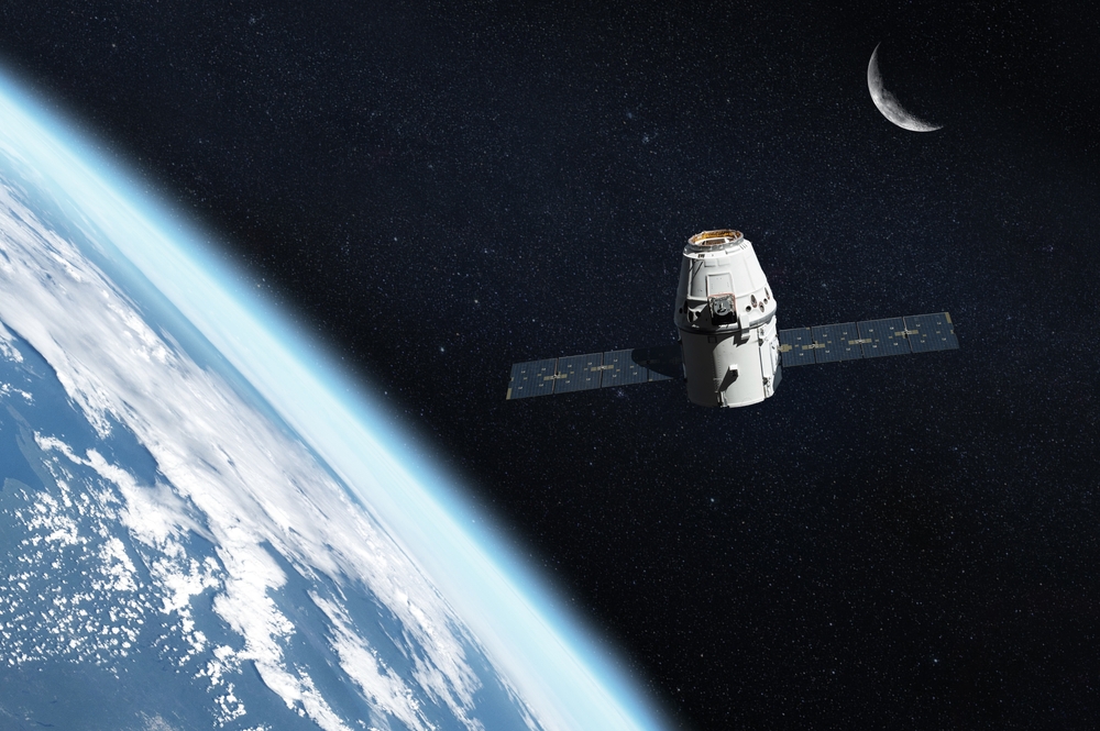A spacecraft orbits Earth with a crescent moon visible in the distant background.