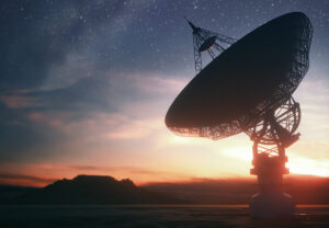 Silhouette of a satellite dish against a starry sky and colorful sunset backdrop.