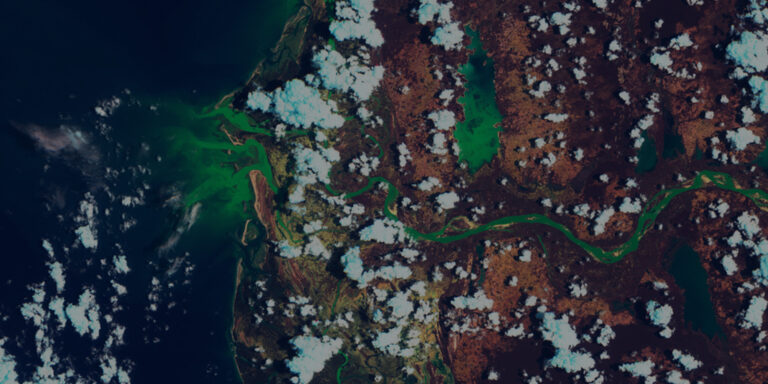Satellite view of a river winding through a brown and green landscape with scattered white clouds.