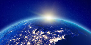 Earth from space with city lights glowing, under a starry sky, and a bright sunrise over the horizon.