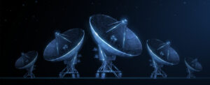 Five illuminated satellite dishes arranged in a row against a starry night sky.