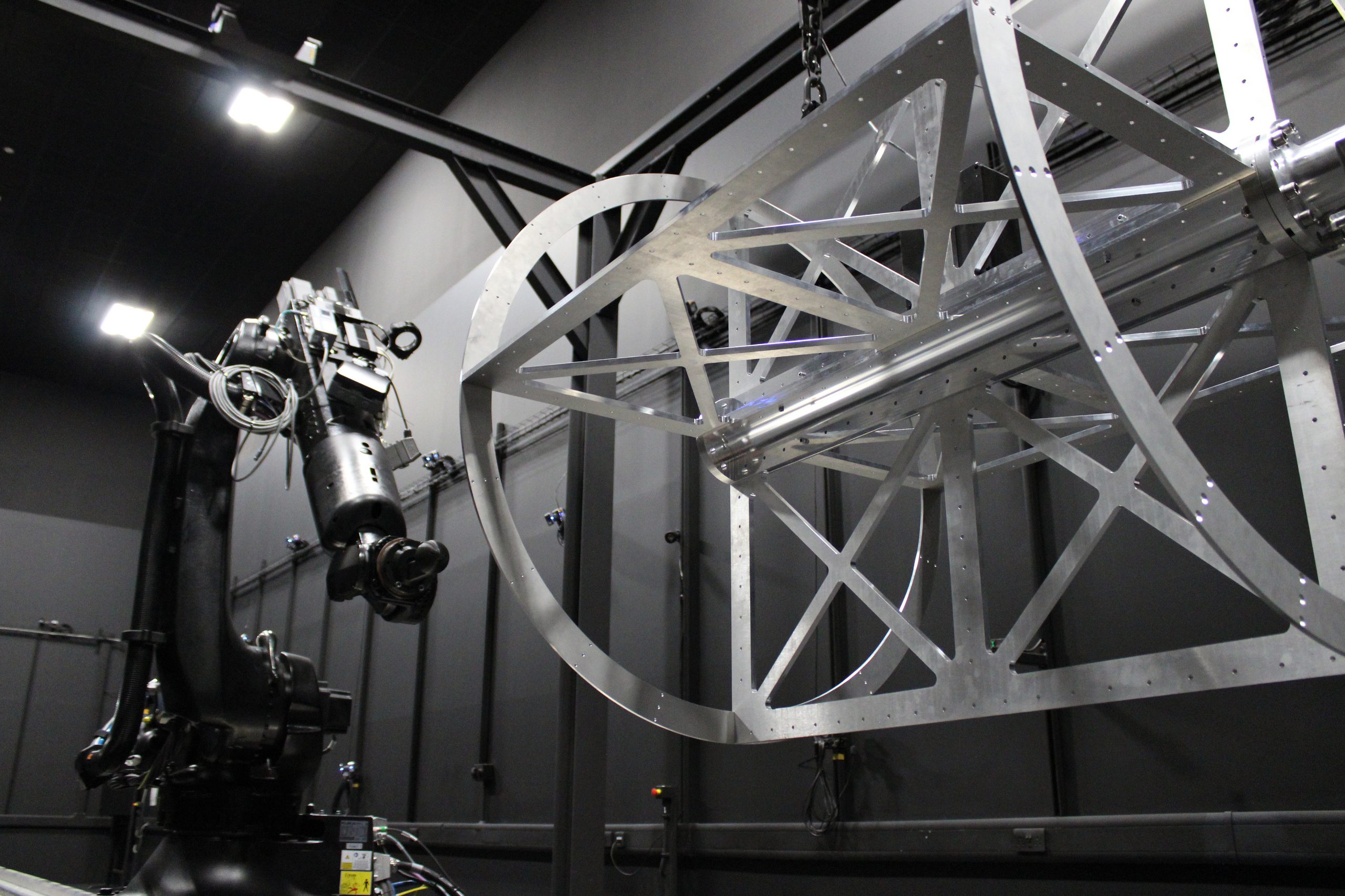 A robotic arm operates near a large metal frame structure in an industrial setting.