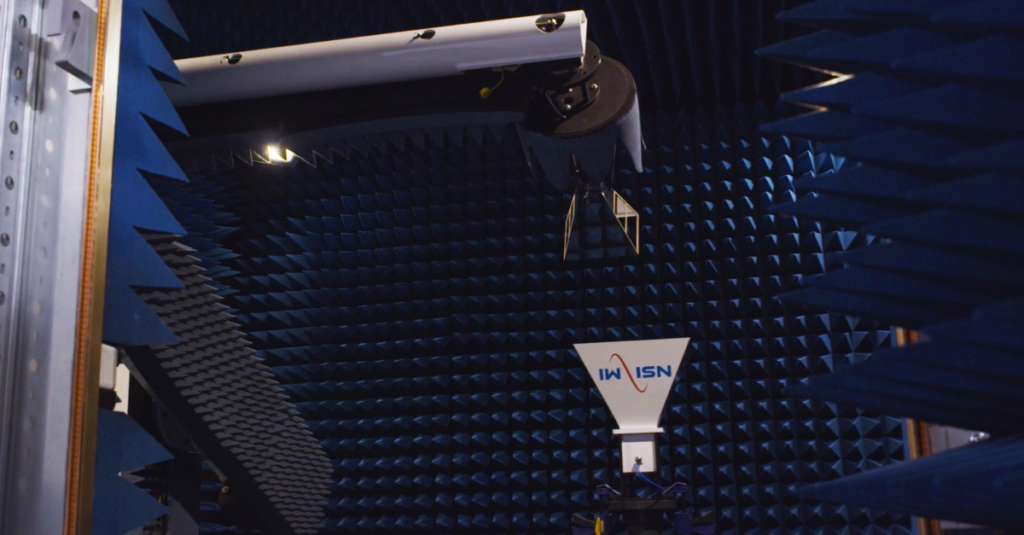 Antenna inside a blue anechoic chamber with foam spikes and testing equipment.