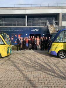 A group of people stand in front of a colorful vehicle and a building with "CATAPULT" signage.