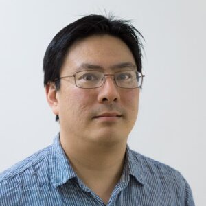 Person with glasses and a striped shirt, looking forward against a plain background.