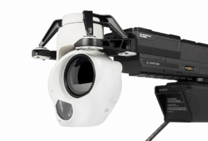 Close-up of a white camera lens attached to a black mount with several electronic components visible.