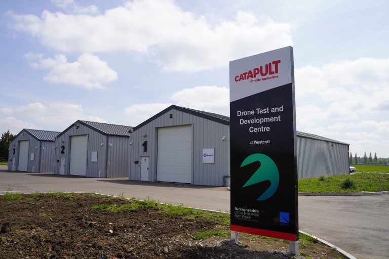 Sign for Catapult Drone Test Centre with nearby industrial buildings and overcast sky.
