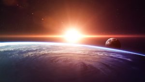 Sun rising over Earth with the moon in the background, viewed from space.