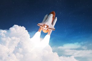 Space shuttle launching into a starry sky with bright flames and smoke below.