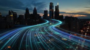 Futuristic cityscape at dusk with neon light trails flowing through skyscrapers.