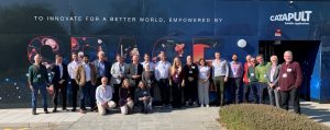 A group of people pose outside a building with a “SPACE” mural and the Catapult Satellite Applications logo.