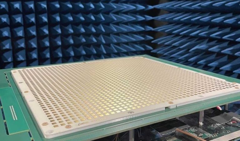 A close-up of a grid-like electronic device in a blue anechoic chamber for signal testing.